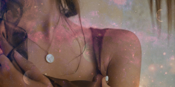 A close-up of a woman wearing a gold Lumina Zodiac Necklace by Luna Charles, engraved with a mother-of-pearl star sign pendant, overlaid with soft pink and purple cosmic textures representing the night sky and celestial energy.